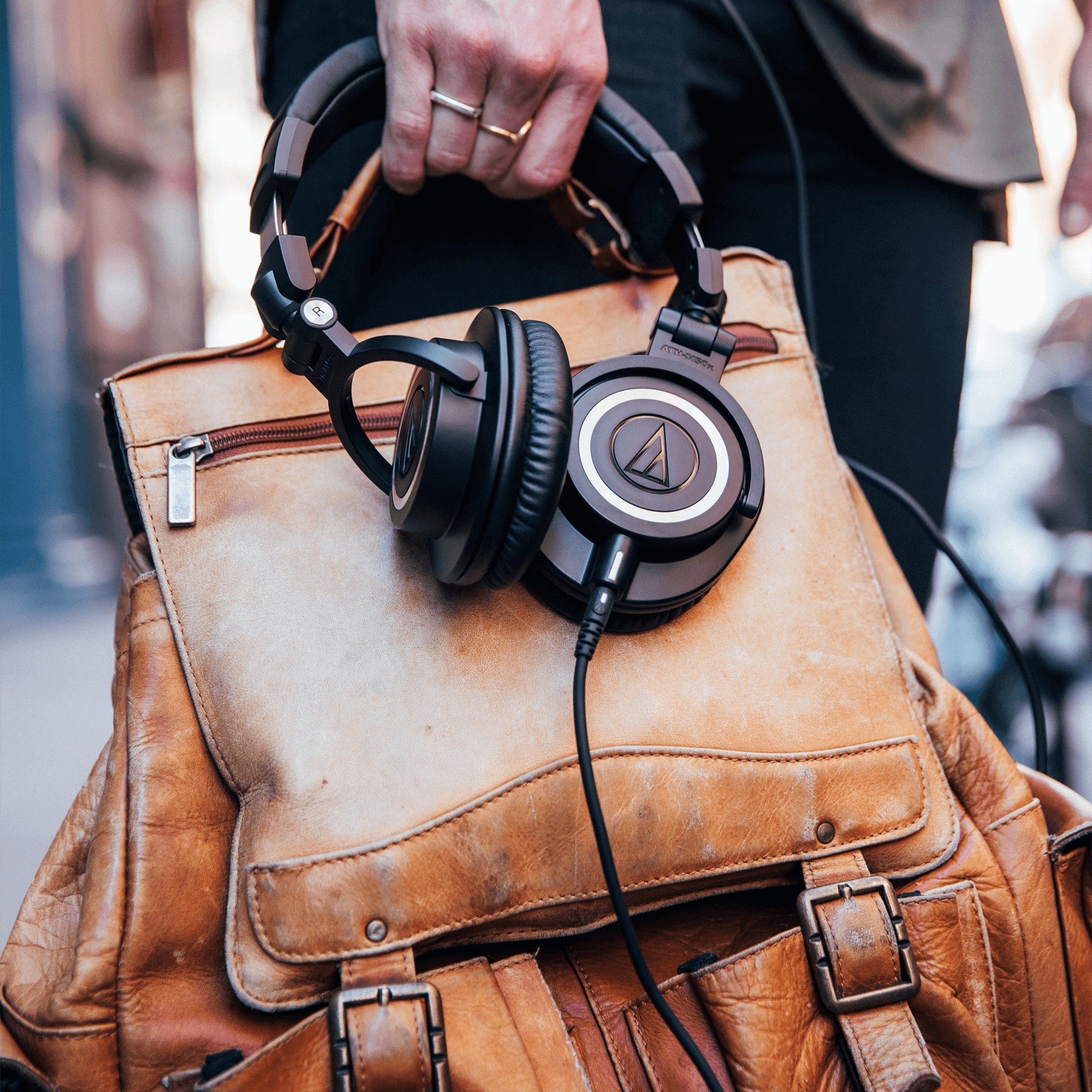 Audifonos ATH M50X agarrados por una persona en la calle